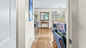 A modern kitchen with a dining area, wooden flooring, and a large window providing natural light.