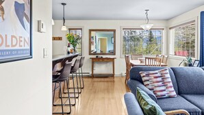 A modern living room with a sofa, a dining table with chairs, and a kitchen area with a bar.