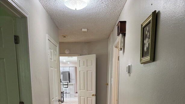 Un couloir doté d’un plancher en bois, de murs blancs et d’un luminaire au plafond.