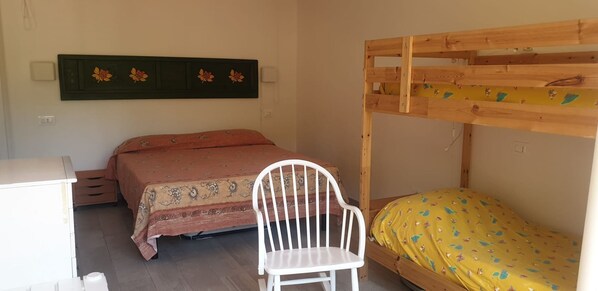 A bedroom with a bunk bed, a single bed, a desk, and a chair.