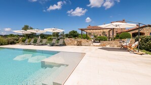 Un área de piscina con agua cristalina, sillas de descanso y sombrillas.