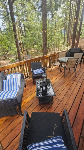 Eine Holzterrasse mit Gartenmöbeln, darunter eine Couch, Stühle und ein Tisch.