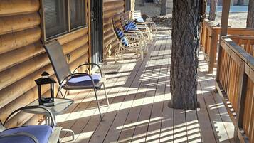 A wooden deck with lounge chairs and a wooden cabin structure.