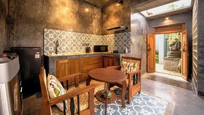 A compact kitchen with a wooden table and chairs, a built-in stove, and a patterned backsplash. - Lanturan Ubud-Villas (Ubud)