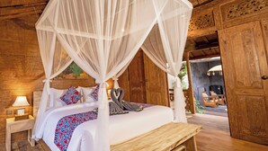 A wooden room with a bed, a nightstand, and a bench. - Lanturan Ubud-Villas (Ubud)