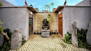 A courtyard with a statue, tiled floor, and stone walls. - Lanturan Ubud-Villas (Ubud)