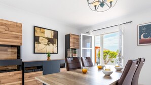 A modern dining area with a wooden table and chairs, a large abstract painting, and a view of the outdoors. - Exclusive Villa Olivia with Private heated Pool (Callao Salvaje)