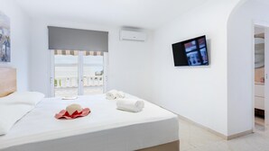 A hotel room with a bed, a TV, a window with a view, and an air conditioning unit. - Exclusive Villa Olivia with Private heated Pool (Callao Salvaje)
