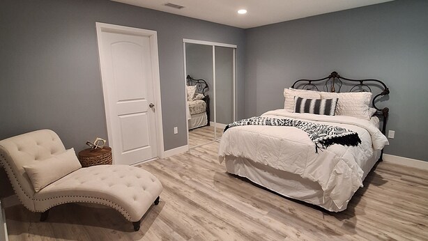 A bedroom with a bed, a chair, a wardrobe, and a door. - Charming 2-bedroom house in Azusa with WiFi and AC (Azusa)
