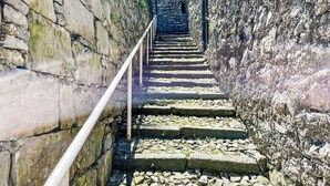 A stone staircase leading up a narrow alleyway with a metal railing.
