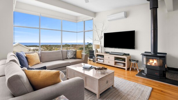 Uma sala de estar moderna com sofá, mesa de centro, televisão e lareira a lenha.