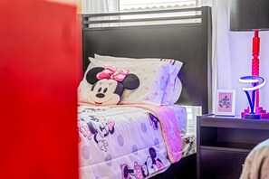 A bed with Minnie Mouse themed bedding, a nightstand with a lamp, and a window with blinds. - 4Br FunOasis /Pool/ BBQ@Solana (Davenport)