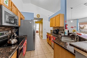 A modern kitchen with granite countertops, stainless steel appliances, and wooden cabinets. - 4Br FunOasis /Pool/ BBQ@Solana (Davenport)
