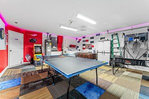 A room with a ping pong table, a refrigerator, a cabinet, and a basketball hoop. - 4Br FunOasis /Pool/ BBQ@Solana (Davenport)