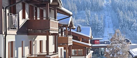 A wooden building with balconies and a ski lift in the background.