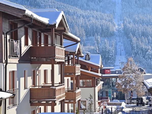 A multi-story building with wooden balconies and a ski lift in the background.