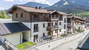 Un hotel de varios pisos con balcones, un área exterior cubierta y vistas a montañas.