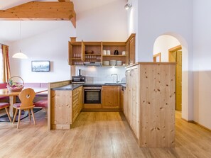 Kitchen features a central island, microwave, stove, and sink, adjacent to a dining area with a table and chairs.