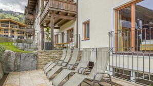 Una terraza con sillones, un muro de piedra y vista a la montaña.
