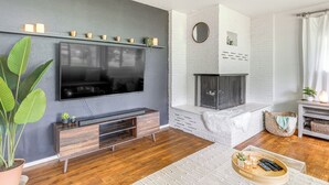 A modern living room with a flat-screen TV mounted on the wall, a wooden entertainment unit, a fireplace, and a large potted plant. - Pregame Pool Matches, 1 Mi to UO Campus (Eugene)