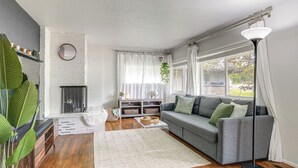 A living room with a grey sofa, a white rug, a coffee table, a fireplace, and a large window with curtains. - Pregame Pool Matches, 1 Mi to UO Campus (Eugene)