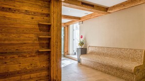 A wooden interior with a tiled floor, a bench, and a door leading to another room.