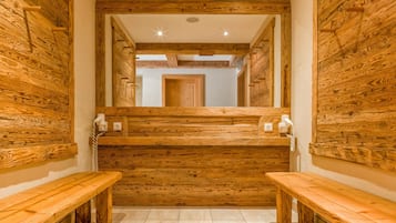 Relax in this serene bathroom with a bathtub, wooden benches, and a large mirror.