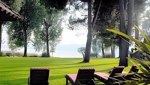 A grassy area with three lounge chairs and a pergola structure.