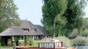 A house with a thatched roof, a dock, and a boat.