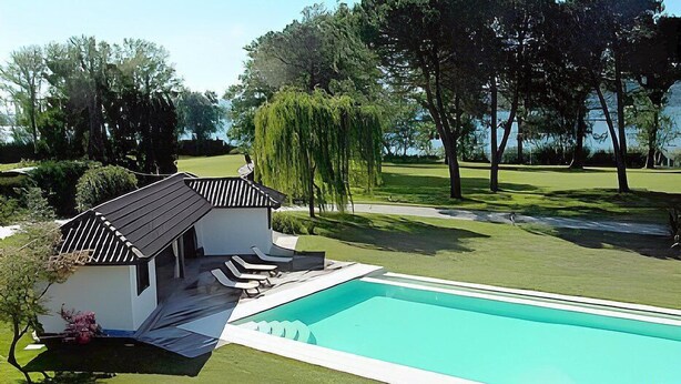 A modern house with a swimming pool, surrounded by lush greenery and trees.