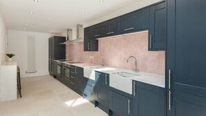 A modern kitchen with dark cabinets, a white countertop, and a hexagonal tile backsplash. - Spacious House, Private Parking & Garden (Gloucestershire)