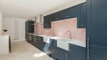 A modern kitchen with dark cabinets, a white countertop, and a hexagonal tile backsplash.
