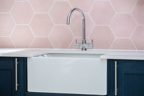 Una cocina con un lavamanos blanco, grifo de acero inoxidable y armarios oscuros.