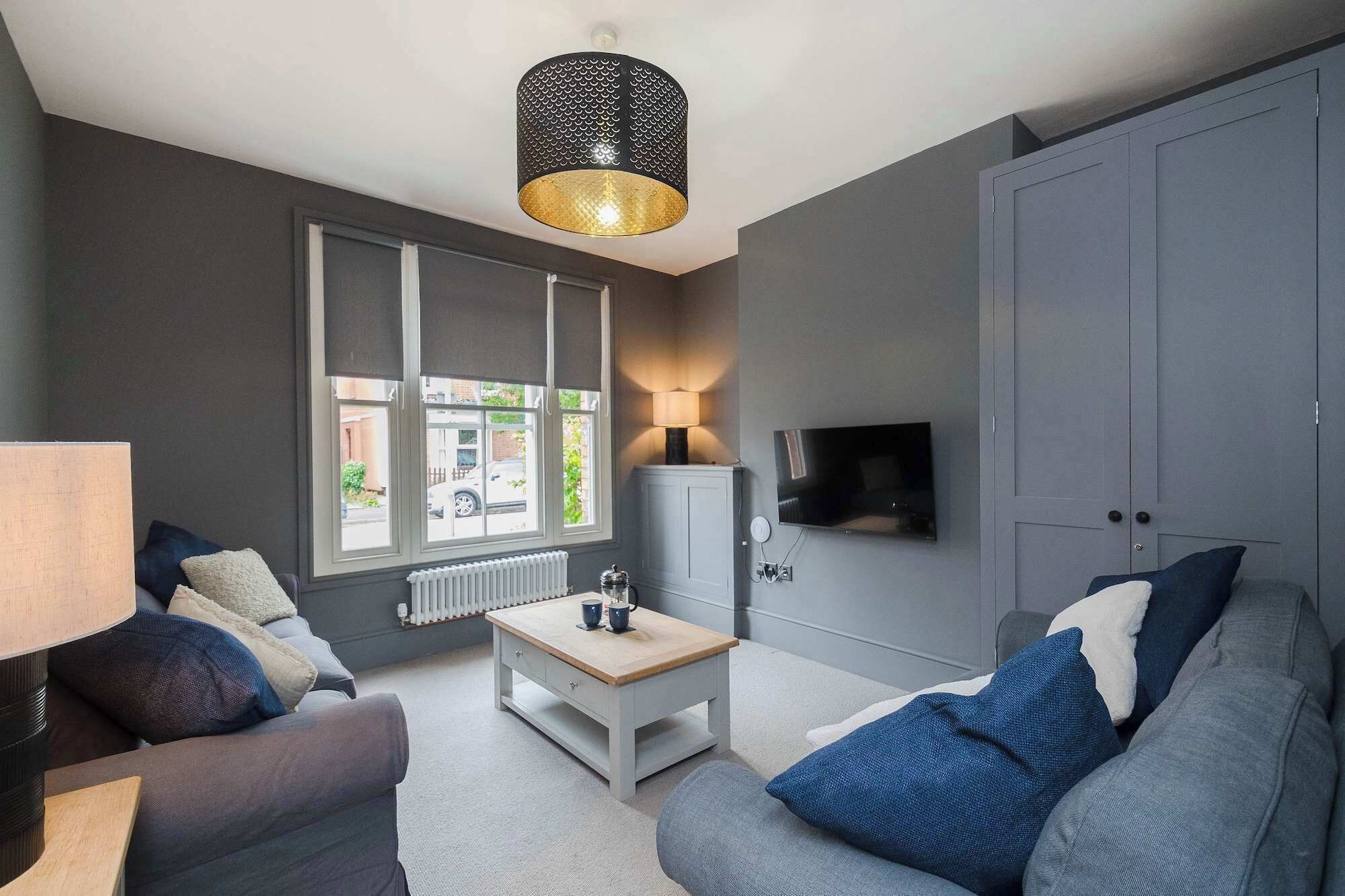 A modern living room with a grey sofa, a white coffee table, and a TV mounted on the wall.