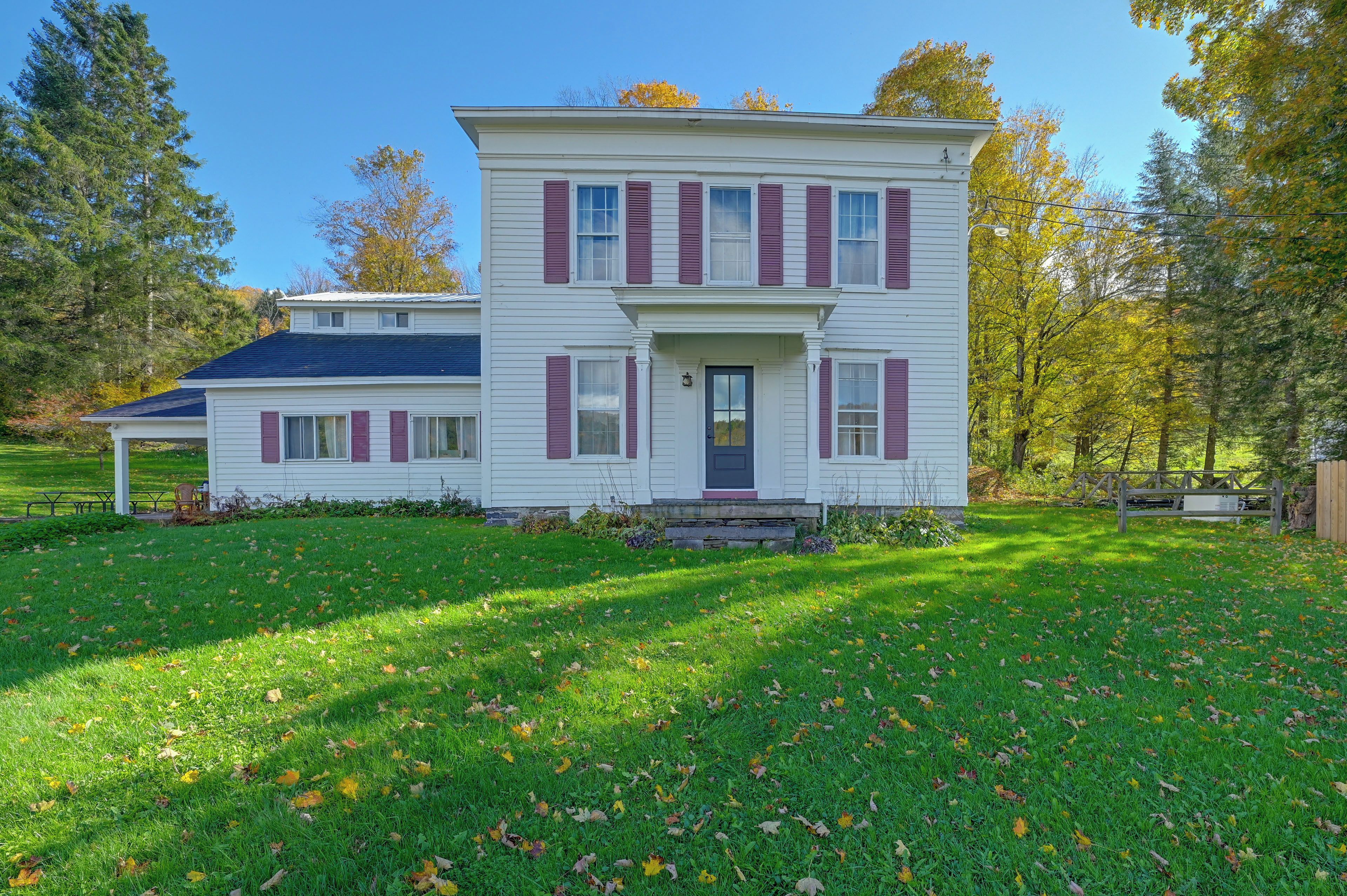 A two-story house with a front porch and a covered patio area.