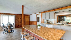 A kitchen with a granite countertop, wooden cabinets, and a dining area with a table and chairs. - Hike & Baseball Near Cooperstown: Home on 30 Acres (Cherry Valley)