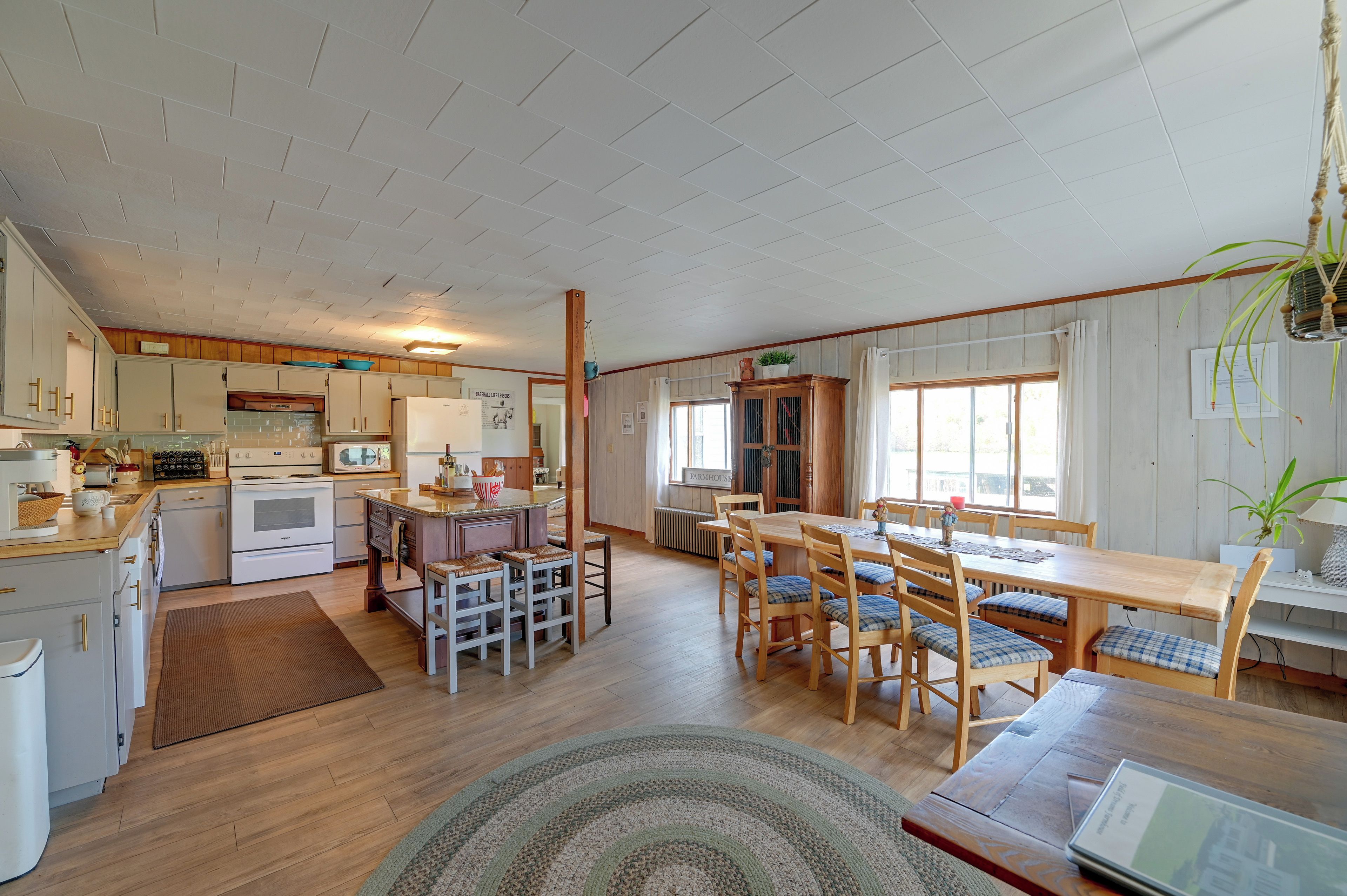 A spacious kitchen with modern appliances, a dining area with wooden furniture, and a large window providing natural light.