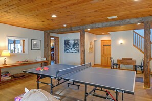 Ein Tischtennistisch in einem Raum mit Holzbalken, einem Fenster und Kunstwerken an den Wänden.