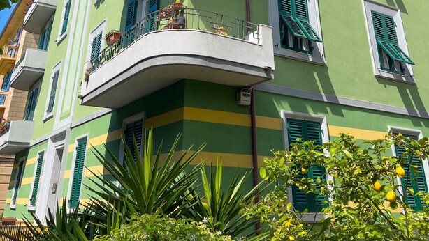 A multi-story building with balconies, green shutters, and a satellite dish. - Spacious apartment with garden, near the beach (Levanto)