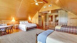 A spacious bedroom with a large bed, a smaller bed, a desk, and a chair. There is a ceiling fan and a window. - Spacious Riverfront Cottage w/ Dock in Green Pond! (Green Pond)