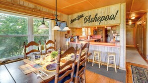A cozy dining area with wooden furniture, a bar area, and large windows offering a view of the outdoors. - Spacious Riverfront Cottage w/ Dock in Green Pond! (Green Pond)