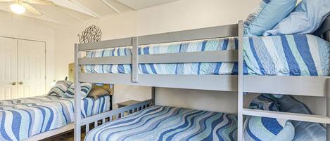 A bunk bed room with striped bedding and a ceiling fan.