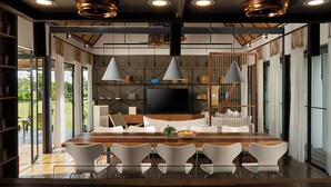 A modern living room with a wooden dining table, white sofas, and a flat-screen TV. - Sré Lodge Living Style Community (Kampot)