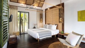 A spacious bedroom with a large bed, a wooden bench, and a view of the outdoors. - Sré Lodge Living Style Community (Kampot)
