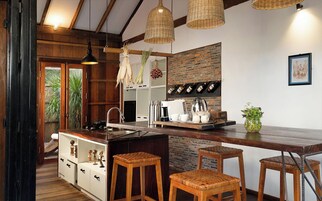 Una cocina rústica con vigas de madera, un salpicadero de ladrillo y un lámpara colgante.