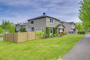 Stylish residential building with a lawn and secure fencing, offering easy access for vehicles and pedestrians.