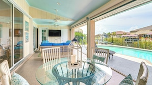A glass-top table with chairs and cushions, a ceiling fan, and a view of a swimming pool and outdoor area. - Dock & Lanai! Waterfront Oasis Near Boca Grande (Port Charlotte)