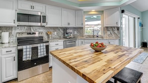 A modern kitchen with white cabinets, a large wooden island, a built-in oven, and a microwave. - Dock & Lanai! Waterfront Oasis Near Boca Grande (Port Charlotte)