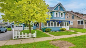 A two-story house with a blue exterior, a white picket fence, and a tree in the front yard.