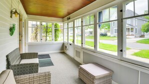 A sunroom with large windows, wicker furniture, and a wooden ceiling.